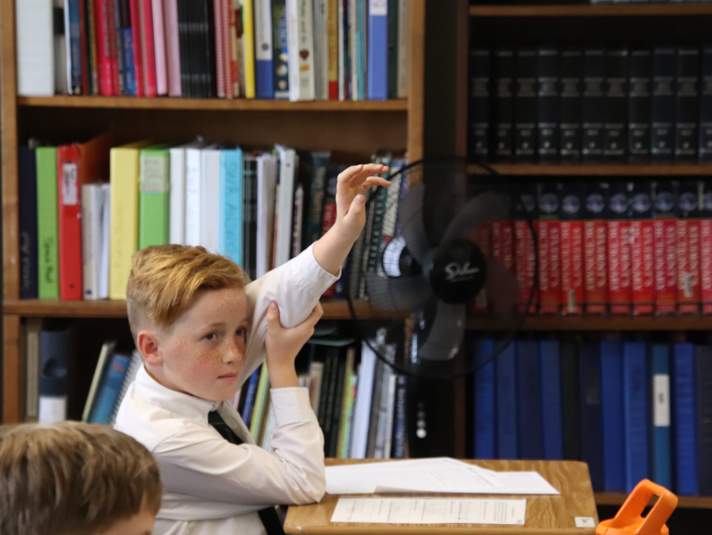 A Geneva Academy student answering in a classroom lined with books, Roseburg, Oregon